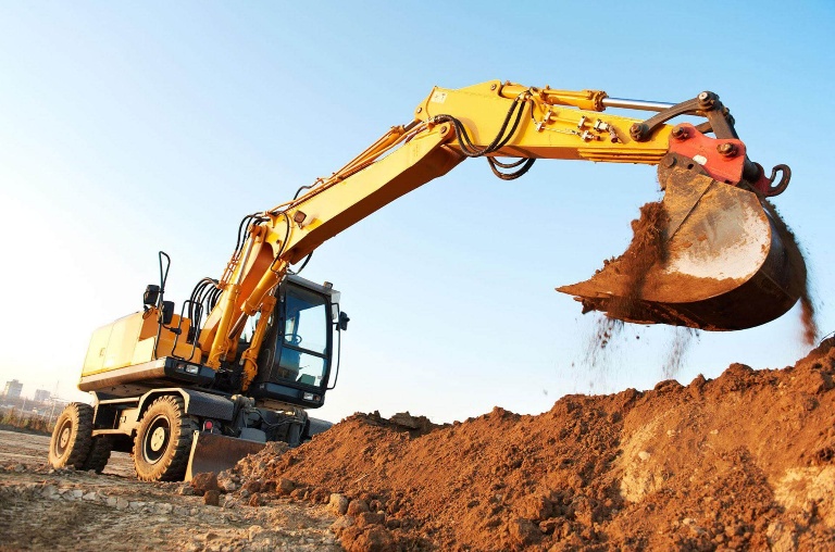 Yellow wheeled excavator tipping soil on a construction site